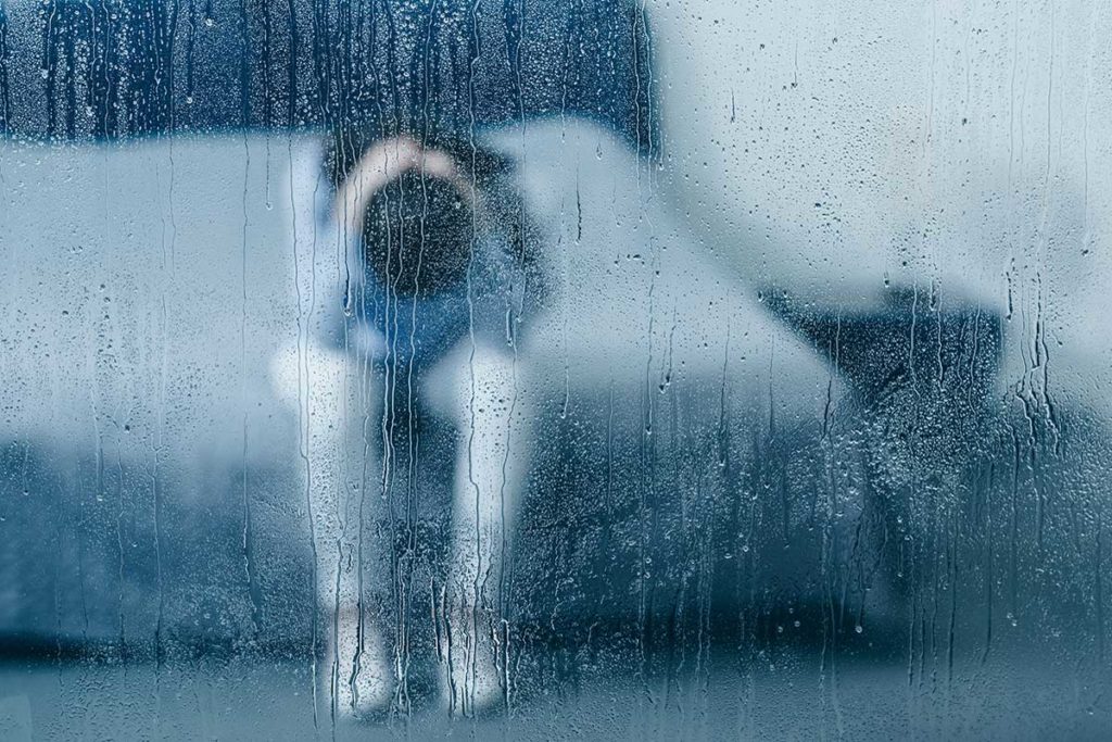 woman sitting on her bed experiencing the signs of seasonal depression